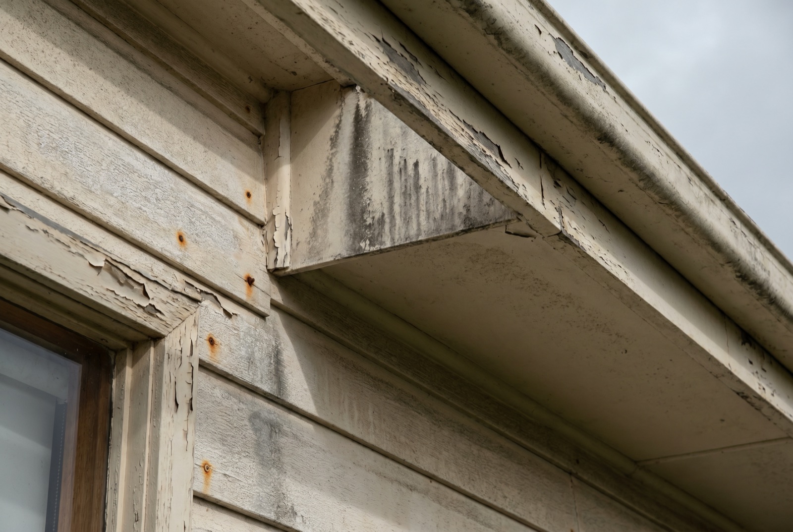 Weathered exterior paint on a Sapphire Coast home showing chalking and mould on south-facing eaves